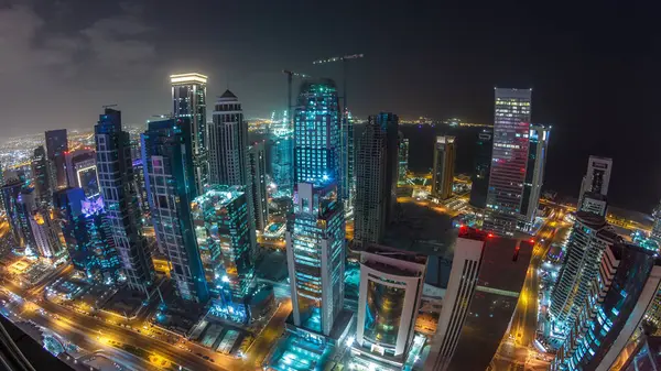 Katar 'ın Doha Zaman Çizelgesi' nde Batı Körfezi bölgesinin ufuk çizgisi. Aydınlatılmış modern gökdelenler geceleri çatıdan gökyüzü manzarası. Yollarda trafik vardı. Fisheye merceği