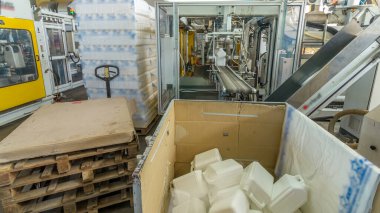 Beyaz plastik bir teneke kutu üretimi için bir fabrika. Fabrikadaki taşıyıcı. Çevre dostu üretim.