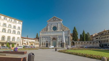 Santa Maria Novella Bazilikası 'nın Floransa' da eşkenar dörtgen zaman dilimi hiperhızlandırılmış görüntüsü. Çiçek yatakları ve yeşil çimenler. İnsanlar bankta oturuyor. Yazın mavi gökyüzü