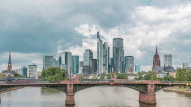Frankfurt 'un, ana nehir ve Ignatz Bubis Köprüsü' yle olan hiperhızlandırılmış silueti. Gökdelenler ve kilise kuleleri dramatik bulutların altındaki suya yansıyor. Frankfurt, Almanya
