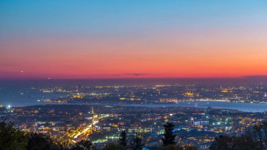 Istanbul night skyline scenery day to night transition timelapse, aerial view over Bosporus channel from Camlica hill. Blue water of Bosporus channel with ship. Traffic on roads