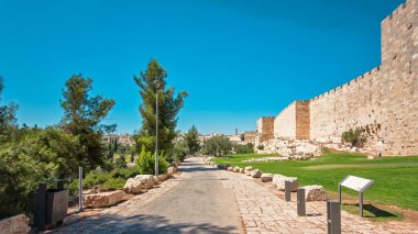 Antik kutsal Kudüs zaman tünelinin savunma duvarı. Parlak güneş tarafından aydınlatılan hiperhız. Yürüyüş yolu ve mavi gökyüzü yakınında harika yeşil çimenler.