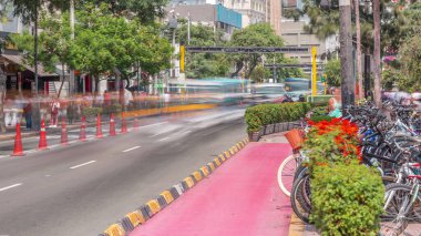 Jose Larco Bulvarı 'nda kırmızı bisiklet pisti ve Miraflores, Lima Peru' da bisiklet park saati. Central Park sağda ve caddede trafik var.
