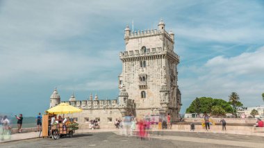 Torre de Belem ya da Belem Kulesi, Lizbon 'un Belem ilçesindeki Rio Tejo' da zaman atlaması yaşıyor. Meyveli büfe. Etrafta dolaşan insanlar. Bulutlu gökyüzü