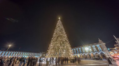 Lizbon 'daki ticaret meydanı, Noel' in aşırı hızıyla aydınlandı. Yükselen bir ağaç ve geceleri kutlayan kalabalıkla. Dekorasyon ve tarihi mimarinin yer aldığı şenlikli atmosferin zamanlaması