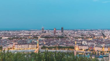 Gün batımından sonra Lyon 'un panoramik hava görüntüsü Fourviere Hill' den gece dönüşümüne kadar. Ufuk çizgisinde Rhone Nehri ve sıcak bir akşamda aydınlanan ikonik kent simgeleri yer alıyor.