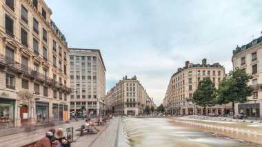 Fransa 'nın Lyon şehrindeki Place de la Republique' in hiperlapesi. Meydanda, tarihi binalarla çevrili büyük bir çeşme var ve insanlar banklarda oturuyor.