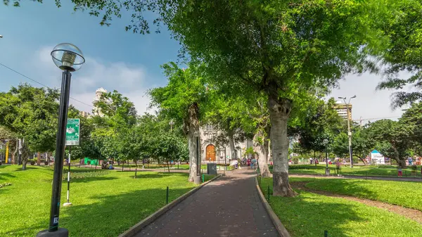 Miraflores Central Park zaman atlamalı yeşil ağaçlar ve Peru başkentindeki çimlerle dinlenmek için bir yer. İnsanlar banklarda oturup yürüyorlar. Lima, Peru