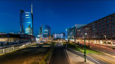 Milano panoramik gökdelenleri, günbatımından sonra, İtalya 'nın Milano şehrinde, Porta Nuova iş bölgesinde günden geceye geçiş. Yollarda trafik vardı. Pencerelerde ışık var. Köprüden üst görünüm