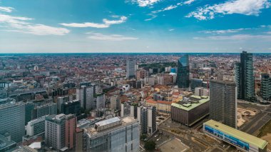 Milano 'nun modern kuleleri ve Garibaldi tren istasyonu yakınlarındaki gökdelenleri çatıdan iş bölgesi zaman çizelgesi manzaralı. Kırmızı çatılı evler. Yazın mavi bulutlu gökyüzü