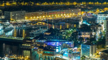 Monako 'nun hava manzarası. Büyük Corniche Yolu' ndan. Gece Zaman Alanı, Monako Fransa. Akşam aydınlatması. Yollarda trafik vardı. Limandaki yatlarla yansıyan yansımalar.