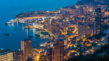 Monako 'nun büyük Corniche yolundan gece geçiş zamanına, Monako Fransa' ya giden hava manzarası. Akşam aydınlatması. Limanın suyundaki yansımalar