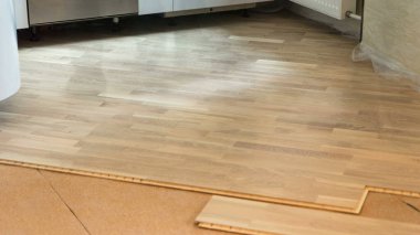 işçi iş timelapse döşeme sırasında substrat önünde ahşap parke yükleme yeşil üniformalı bir marangoz. Hazırlık çalışmaları