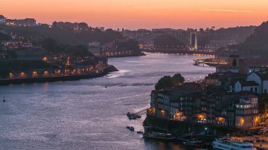 Day to night transition aerial view of the historic city of Porto, Portugal panoramic timelapse from the Dom Luiz bridge. Illuminated waterfront and curved river from above