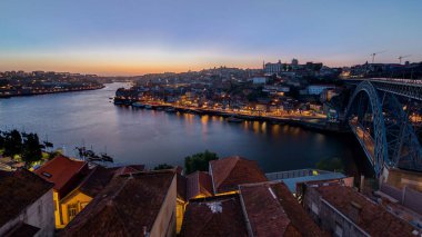 Panorama old city Porto at river Duoro, with Port transporting boats day to night transition timelapse with the Arrabida bridge after sunset, Oporto, Portugal