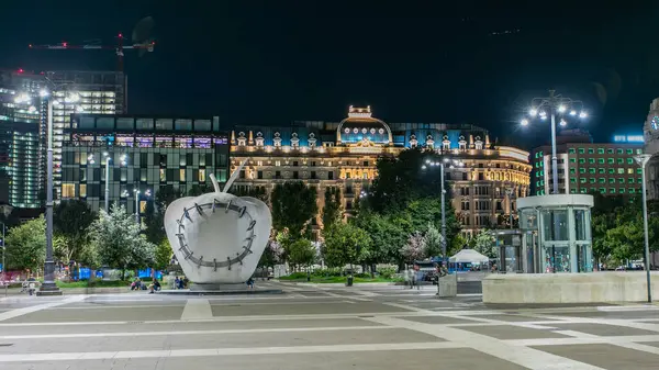 Anıtsal Reintegrated Apple Milan'ın Merkez Tren İstasyonu, Piazza Duca d'Aosta gece timelapse önünde heykel. Aydınlatılmış binalar. Yaz günü, yeşil ağaçlar