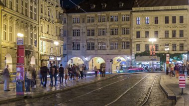 Prag 'daki tramvay durağında insanların olduğu ışıklı malostranske namesti meydanının gece görüşü. Aziz Nicolas Kilisesi 'yle ünlüdür. PRAG, ÇEK CUMHURİYETİ