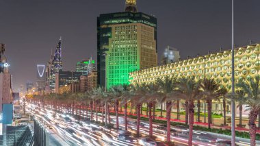 Suudi Arabistan, Riyad 'daki Kral Fahd Yolu' nun hava-gece zaman çizelgesi. Aydınlatılmış Riyad Ulusal Kütüphanesi yakınlarında modern kuleler ve gökdelenlerle çevrili araçlar ve taksilerle dolu.