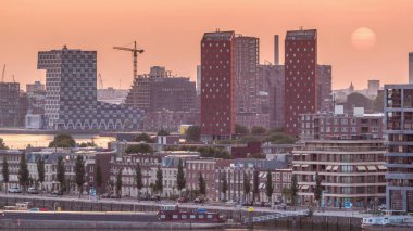 Hollanda, Rotterdam 'da gün batımında Katendrecht Yarımadası ve Maashaven Limanı' nın panoramik zaman çizelgesi. Şehir silueti, modern gökdelenler ve geleneksel Hollanda rıhtım evleri