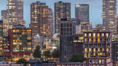 Rotterdam, Hollanda 'daki Katendrecht yarımadası ve Maashaven limanının hava ve gece geçiş zamanı. Günbatımından sonra parlayan pencereleri olan modern gökdelenler.