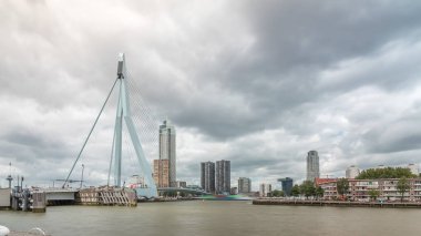Rotterdam, Hollanda 'daki Maas Nehri' ni kapsayan Erasmus Köprüsü zaman atlaması. Hollanda 'nın en büyük kablo destekli baskülü köprüsü gökdelenleri, rıhtımdaki tekneleri ve dramatik bulutlu gökyüzü arkaplanı