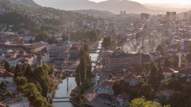 Bosna-Hersek 'in tarihi Saraybosna şehir merkezinin panoramik hava manzarası, gün batımından önce Miljacka nehri üzerindeki ünlü binalar ve köprüler
