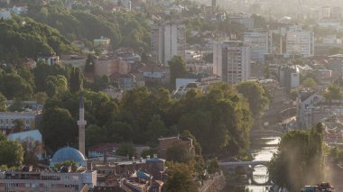Saraybosna 'nın tarihi şehir merkezinin panoramik hava manzarası, Bosna-Hersek' in camisi, ünlü binalar ve Miljacka nehri üzerindeki köprülerle gün batımından önce