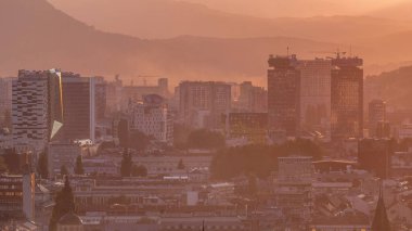 Bosna-Hersek 'in tarihi Saraybosna şehir merkezinin panoramik hava manzarası, gün batımından önce ünlü binalar ve turuncu sislerle dolu