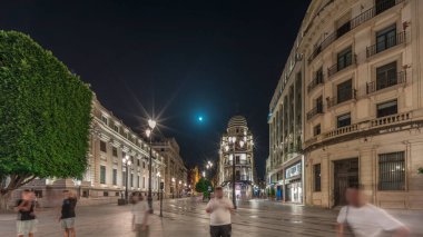 Avenida de la Constitucion gece vakti Seville, İspanya 'da aşırı hız. Iconic Adriatica binası akşam parlıyor. Modern sokak lambaları, yayalar ve şehir atmosferine sahip tarihi mimari