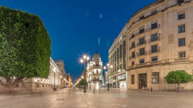 Avenida de la Constitucion, Seville, İspanya 'da günden geceye zaman dilimi. Modern sokak lambaları, yayalar ve kentsel atmosferi olan tarihi mimari. Iconic Adriatica binası gün batımından sonra parlıyor.