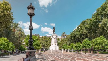 Seville 'deki Plaza Nueva' da, yeşil ağaçlar ve tarihi binalarla çevrili Kral San Fernando 'nun binicilik heykeli yer alıyor. Mavi gökyüzünün altında manzaralı bir şehir alanı
