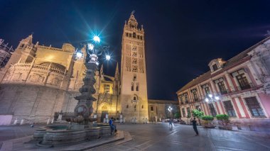 La Giralda ve Seville Katedrali geceleri aşırı hızlanarak altın ışıklarla parıldıyor. Tarihi çan kulesi, gotik detaylar ve aydınlatılmış sokaklar Sevilla, İspanya 'da büyülü bir atmosfer yaratıyor.