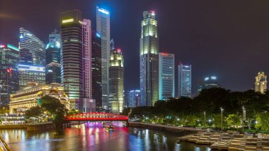 Singapore business district skyscrapers in the night time with water reflections timelapse hyperlapse. Bridge over a river. Illuminated towers with blinking lights in windows