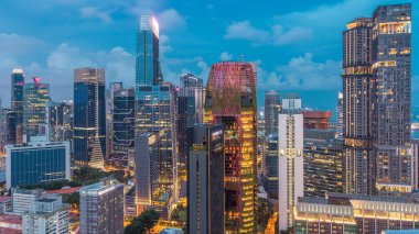 Singapur 'daki şehir merkezinin havadan görünüşü günden geceye geçiş zamanı çatıdan. Modern kuleler ve gökdelenler akşam aydınlandı.