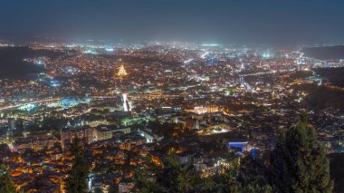 Alacakaranlıkta Tiflis şehri, Gürcistan 'dan gece geçiş zamanı. Şehir merkezinin ve Tiflis 'teki Kura Nehri' nin üst manzarası. Gün batımından sonra Gürcistan başkentinin havadan görünüşü