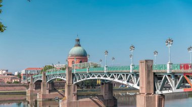 Garonne Nehri 'nin üzerindeki Saint Pierre Köprüsü' nde su ve La Grave Hastanesi 'nin arka planında bulutlu mavi bir gökyüzünün altında yansımaları var. Klasik sokak lambaları cazibe katar. Toulouse, Fransa
