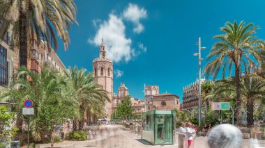 Valencia, İspanya 'da Plaza de la Reina' nın panoramik zaman atlaması. Tarihi bir kilise kulesi, hareketli kafeler ve sıcak Akdeniz semaları altında palmiyeleri olan merkezi bir çeşme..