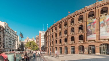 Panorama, Nord istasyonu yakınlarındaki Bullring of Valencia (Plaza de Bous) zaman ayarlı boğa güreşi müzesini gösteriyor. İnsanlar tarihi amfi tiyatronun etrafında mavi bir arkaplanla dolaşıyorlar. Valencia, İspanya.