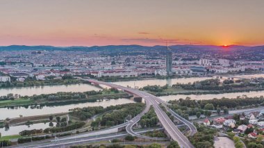 Viyana üzerinde gökdelenler, karayolu kavşağı ve Avusturya 'da nehir kenarındaki gezinti zamanı olan günbatımının hava manzarası. Tuna Kulesi 'nden akşam silueti