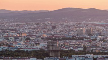 Avusturya 'da gökdelenleri, tarihi binaları ve dağları olan Viyana şehrinin hava panoramik manzarası. Tuna Kulesi 'nden gün batımından önce akşam silüeti