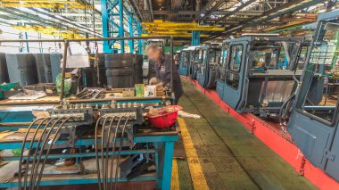 Konveyör montajı, traktörün gövdesini büyük endüstriyel fabrika zaman diliminde sahneleyecek. Kabin montajı, kurulum parçaları özel bir masada.