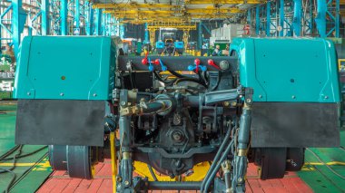 Konveyör montajı, traktörün gövdesini büyük endüstriyel fabrika zaman diliminde sahneleyecek. Çerçeve montajı, yeni parçalar yükleyen işçiler.