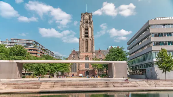 Laurenskerk 'in (Saint Lawrence Kilisesi) Grotekerkplein, Rotterdam' daki hiperlapesi. İnsanlar mavi bulutlu gökyüzünün altında çimlerde dinleniyorlar. Kanal merdivenlerinin yanında saati olan tarihi çan kulesi. Hollanda