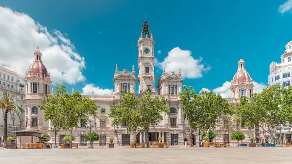 Valencia Belediye Binası (Ajuntament de Valencia) Plaza de Ayuntamiento 'da zamanaşımına uğradı. Mavi bulutlu gökyüzünün altında saat kulesi olan tarihi bir bina. İspanya 'nın ana meydanında gezinen insanlar