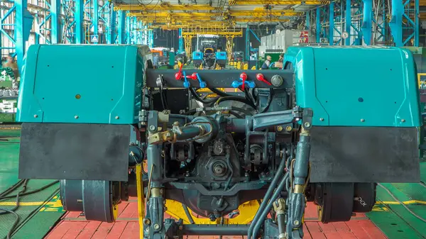 Konveyör montajı, traktörün gövdesini büyük endüstriyel fabrika zaman diliminde sahneleyecek. Çerçeve montajı, yeni parçalar yükleyen işçiler.