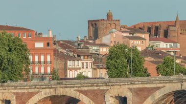 Garonne Nehri ve Pont Neuf zaman çizelgesi Notre-Dame de la Dalbade Kilisesi Fransa 'nın Toulouse şehrinde. Bu Rönesans kemer köprüsü mavi gökyüzünün altındaki suya yansıyor. Yeşil ağaçlı rıhtım