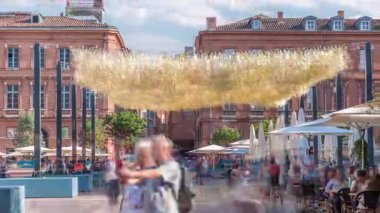 Fransa 'nın Toulouse şehrinde Capitole Meydanı' nda. İkonik kırmızı tuğlalı tarihi ön cephelerde açık hava kafeleri, beyaz şemsiyeler ve süslemeli ışıklandırmalar var. Canlı bir yaya istikameti.