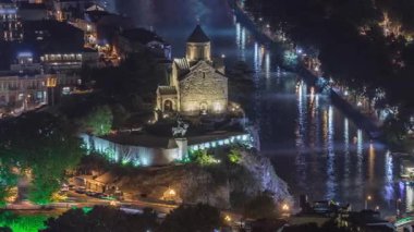 Metekhi Bakire Meryem Varsayımı Kilisesi 'nin hava gece zaman çizelgesi ve Kura Nehri üzerindeki Kral Vakhtang Gorgasali Heykeli. Köprüde trafik vardı ve rıhtım aydınlatılmıştı. Tiflis, Gürcistan.