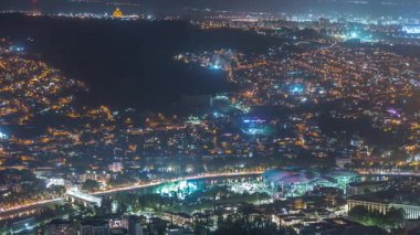 Aydınlanmış Tsminda Sameba Katedrali ya da Tiflis 'in Kutsal Üçlü Katedrali ve Kamu Hizmeti Salonu' nun gece zaman çizelgesi. Tiflis, Gürcistan 'daki ana katedral. Arka plandaki evler