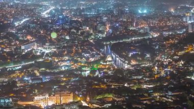 Rike Park 'ın olduğu şehir panoraması gece yukarıdan. Tiflis 'in eski bir kasabasındaki modern şehir parkı. Tarihi ve modern binalarla aydınlatılmış Barış Köprüsü ve hava balonu. Georgia